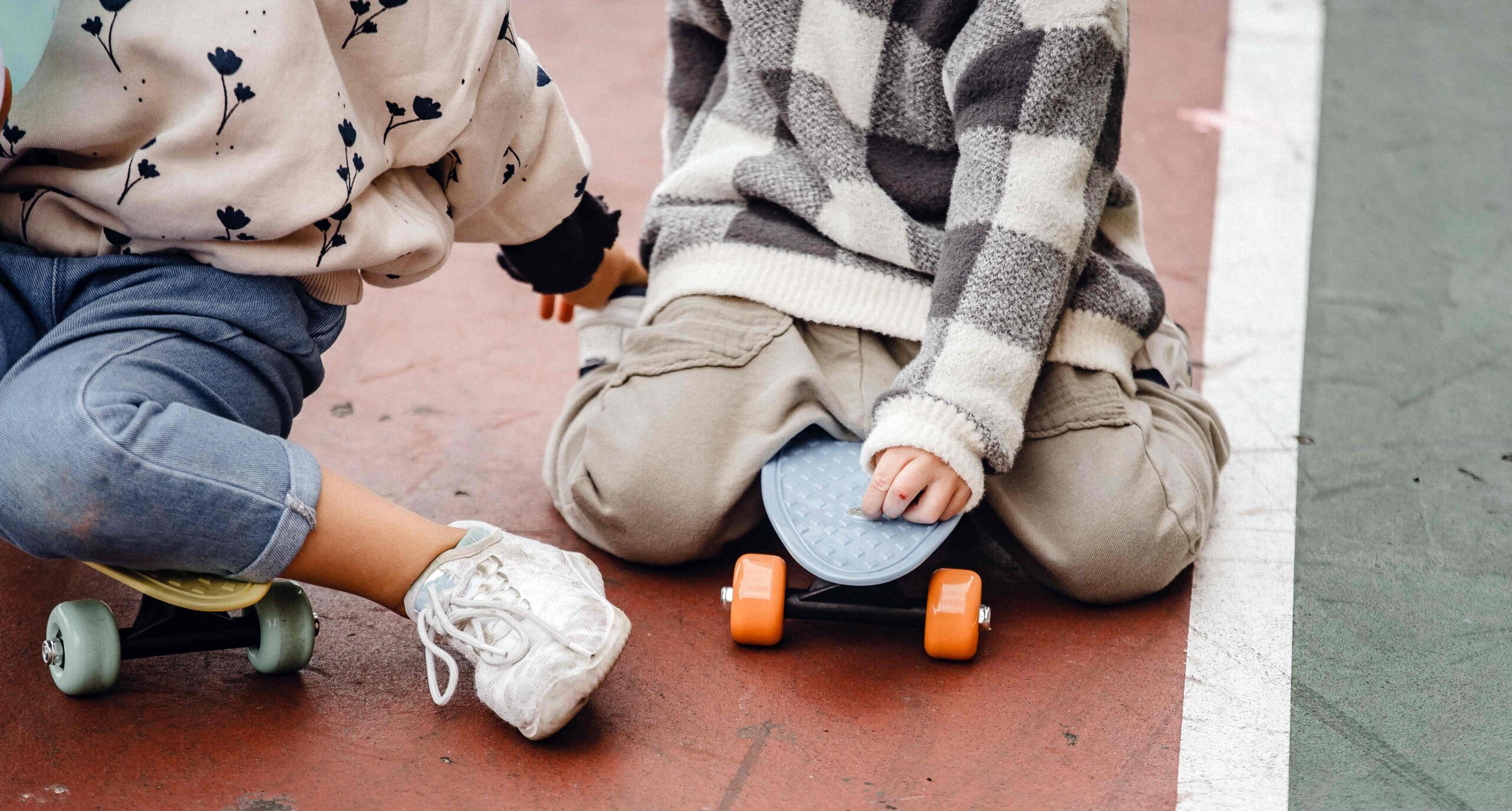 two children sitting on skateboards