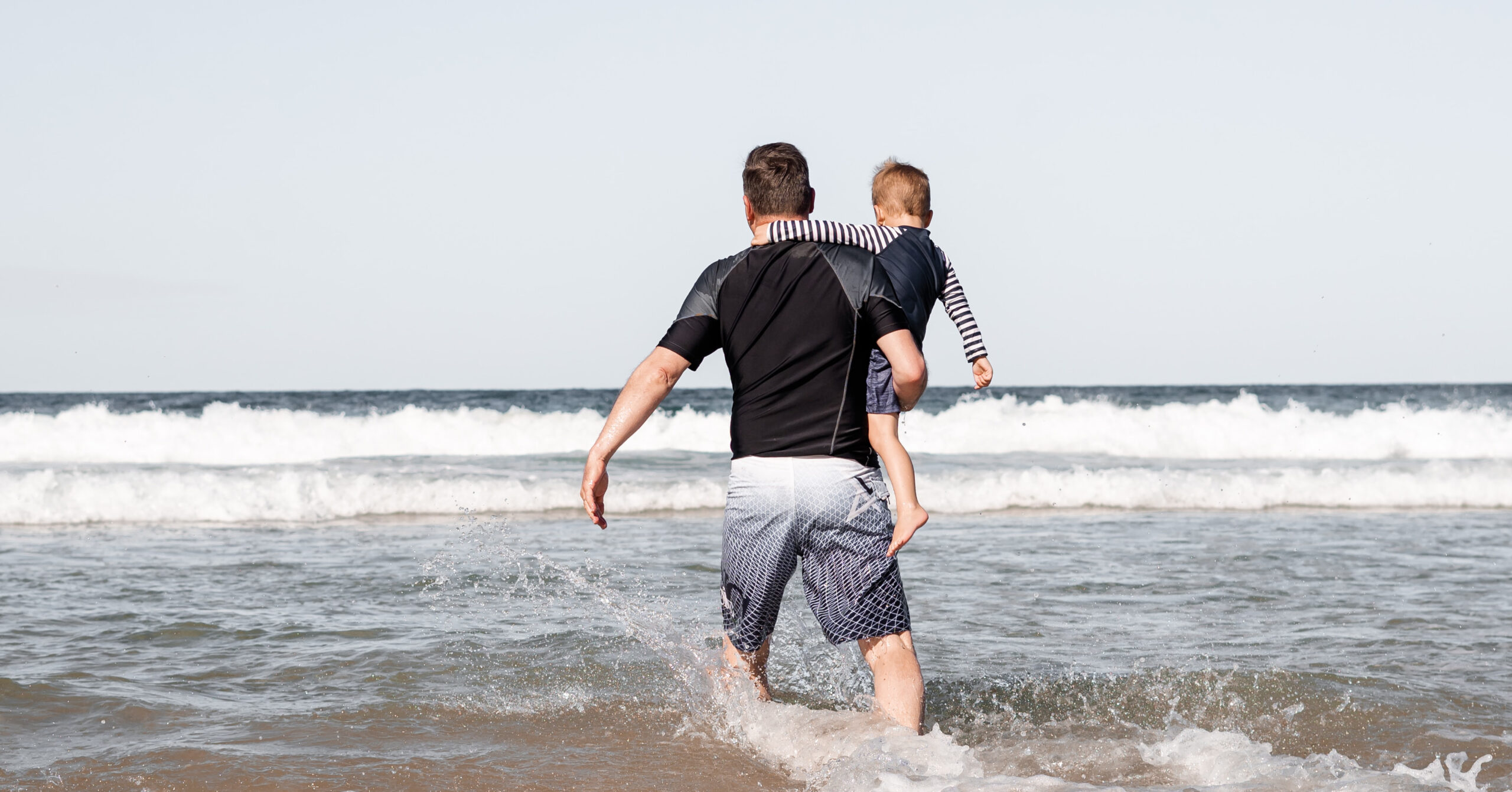 parent carrying child in the sea