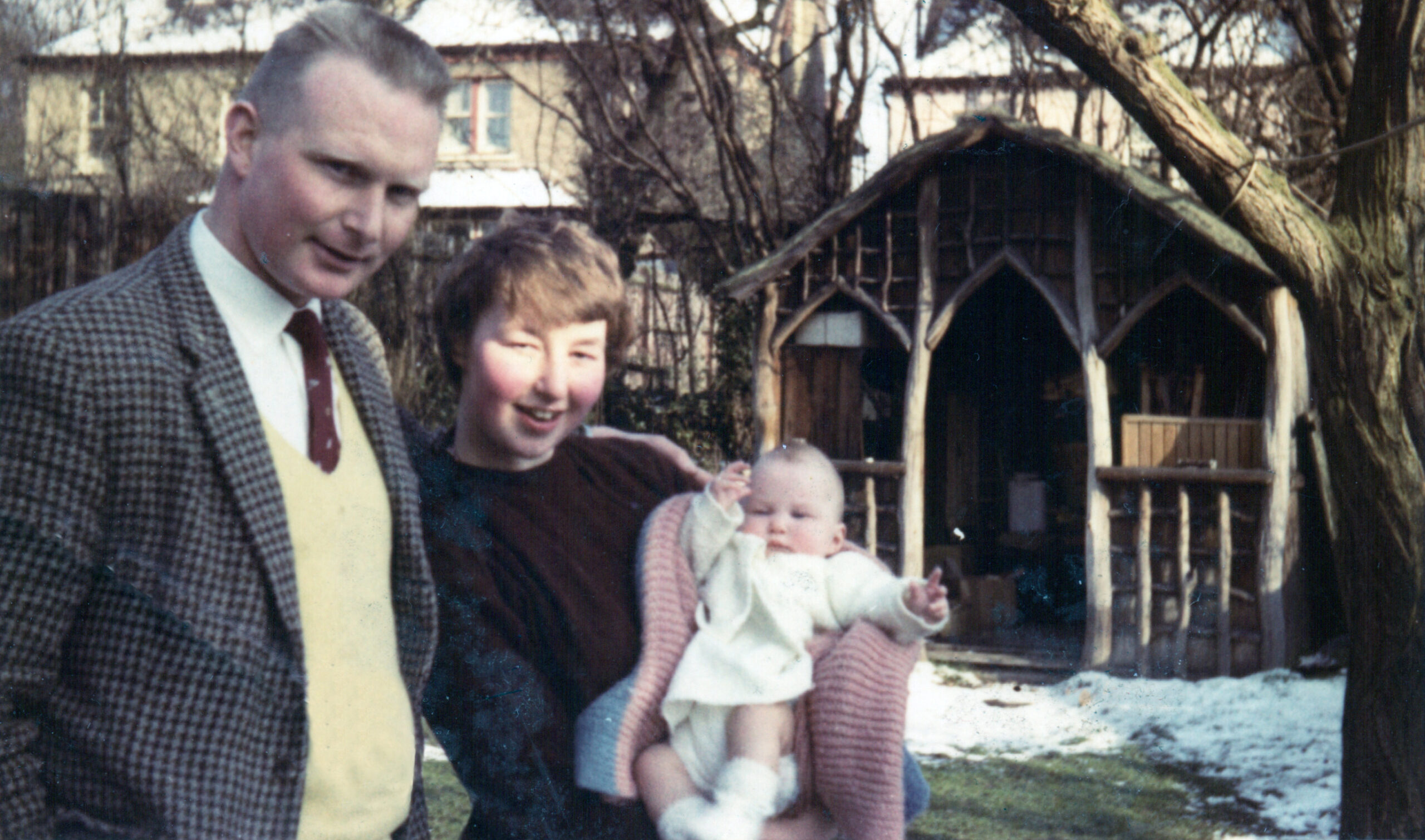 Father, mother and baby in mother's arms, in the garden, 1963
