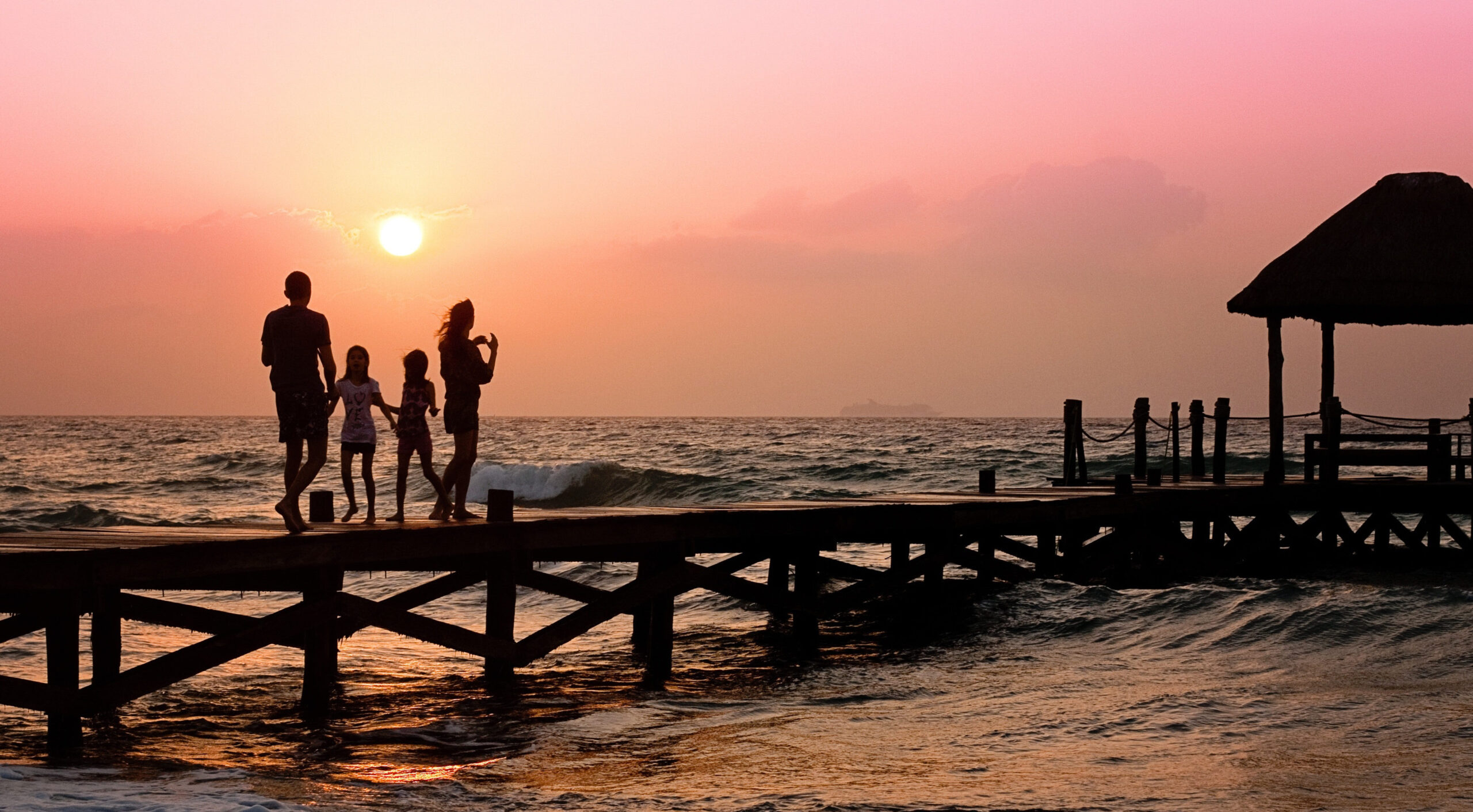 a family on a walkway over water at sunset