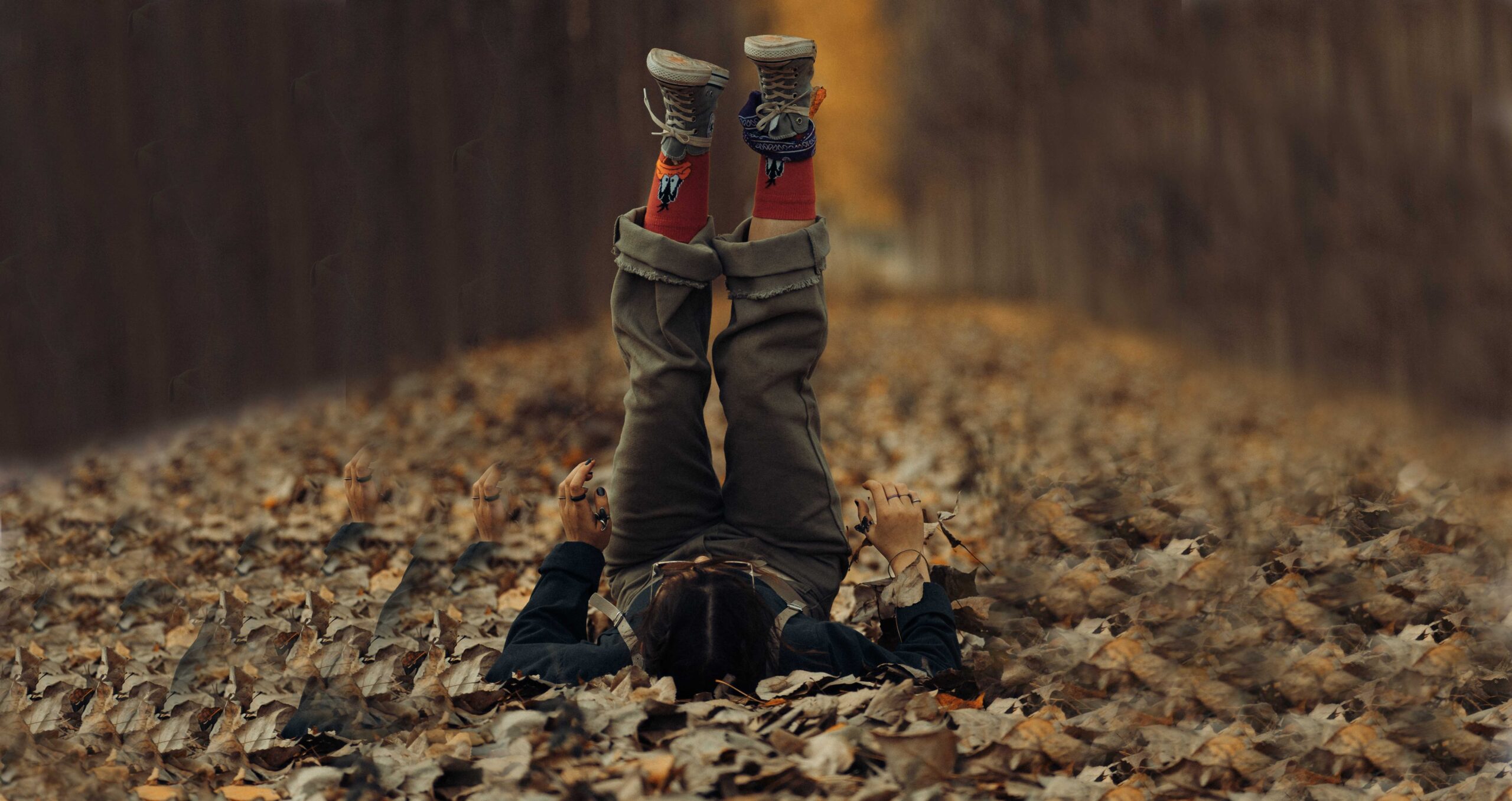a child lying on autumn leaves, legs straight up, vertically