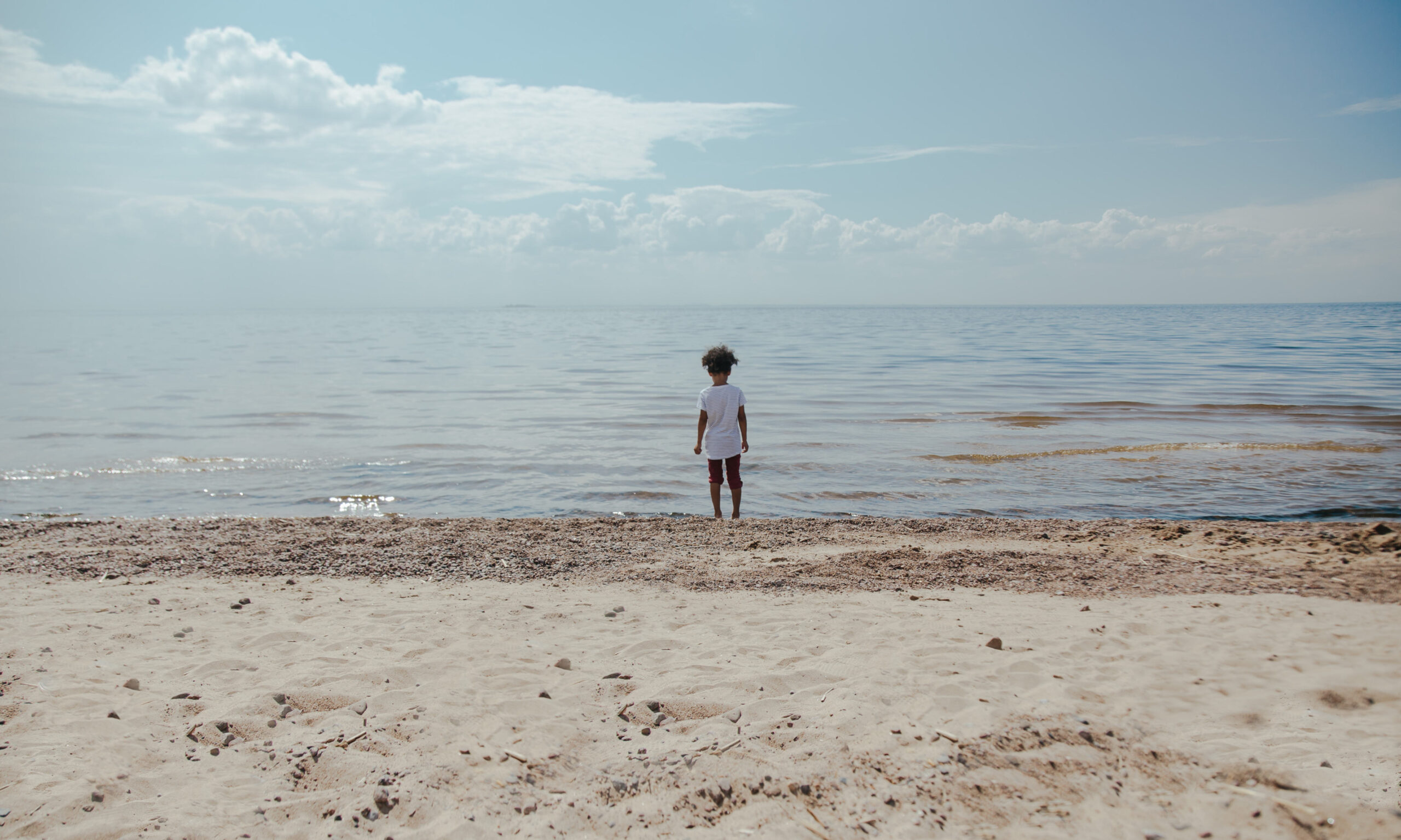 a child standing on the seashore looking out to sea