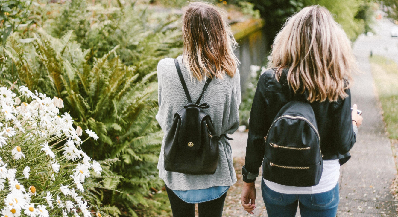 two girls walking with backpacks on