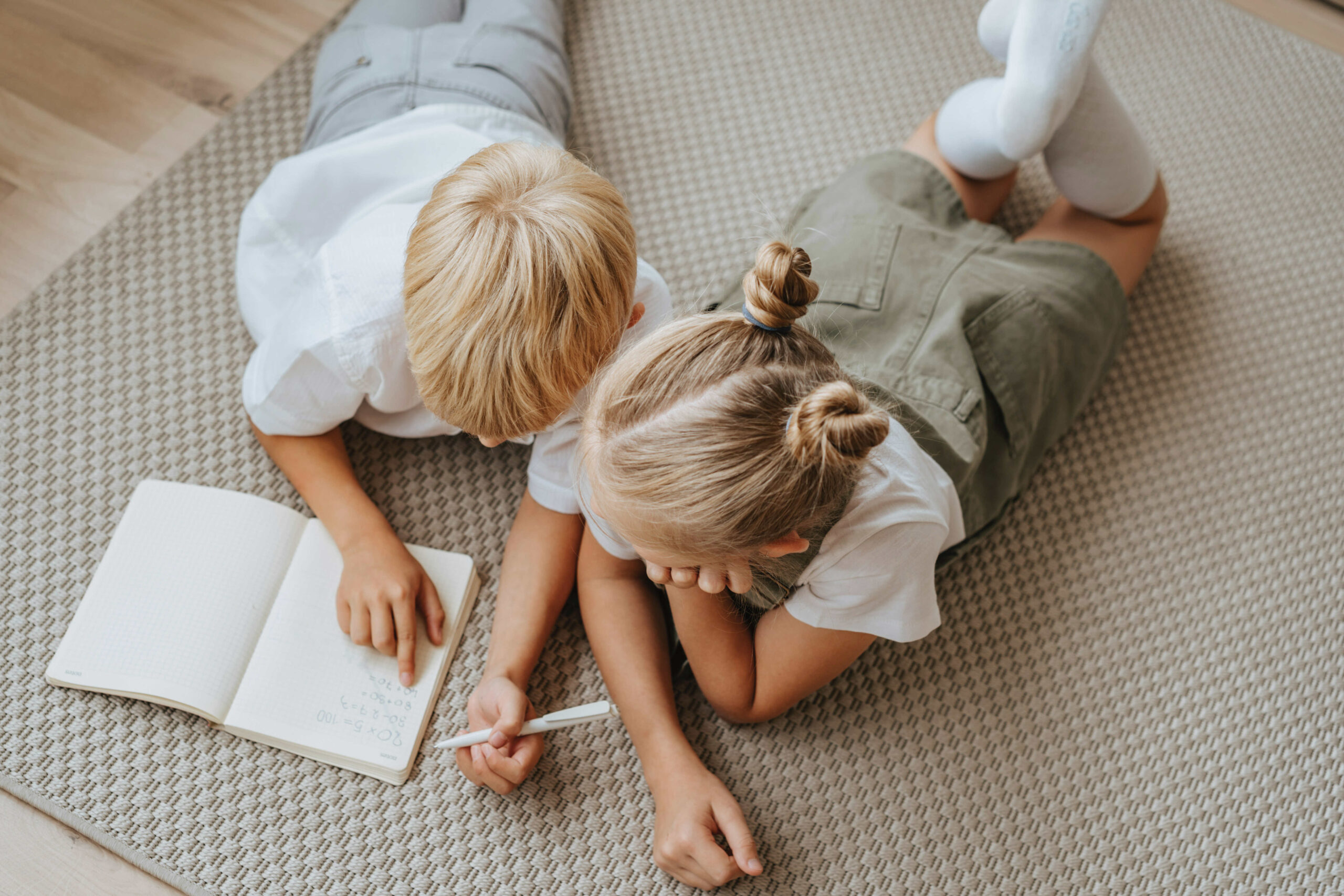 two children lying on the floor reading a book together