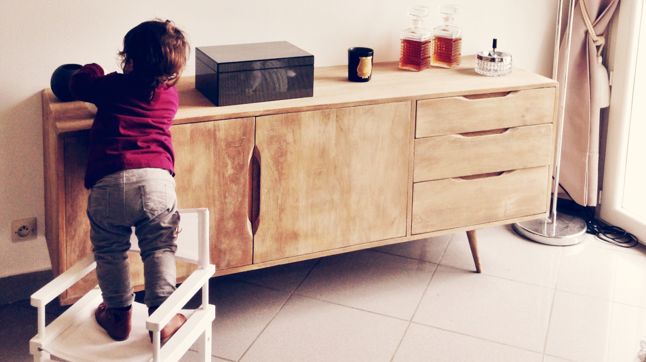 a young child standing on a chair to reach something on a cabinet