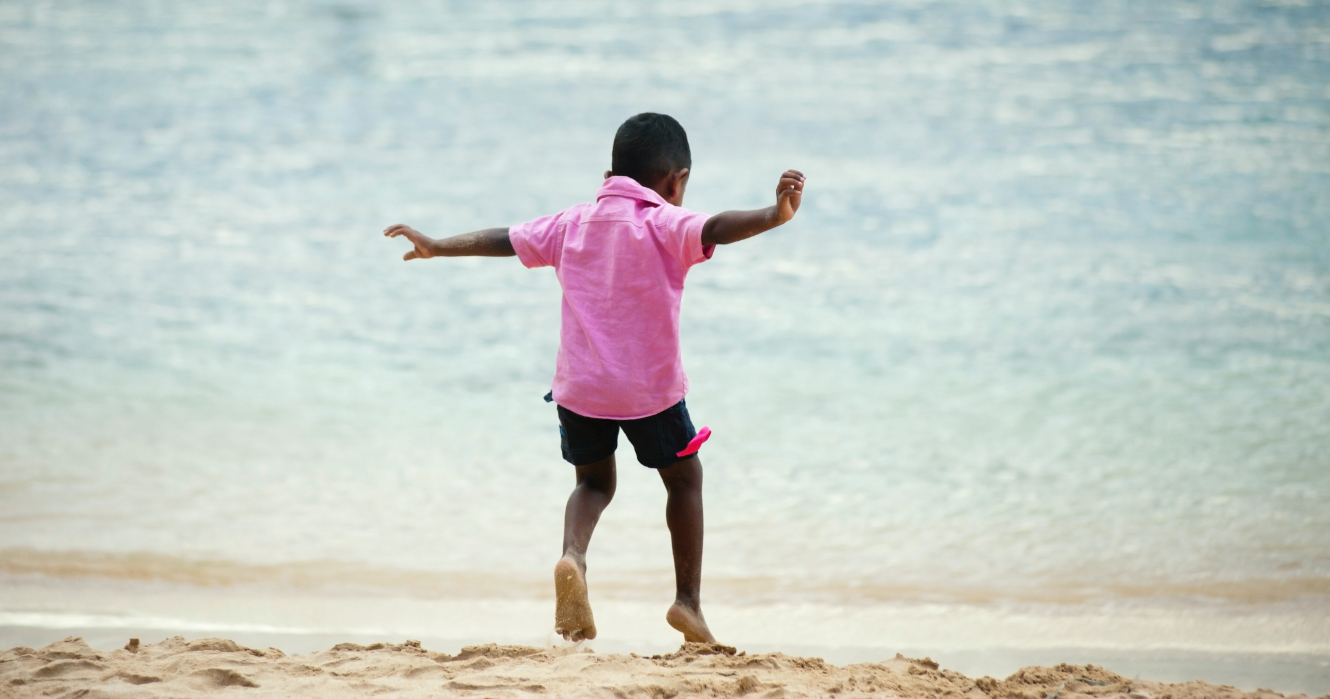 a child leaping on a sandy beach