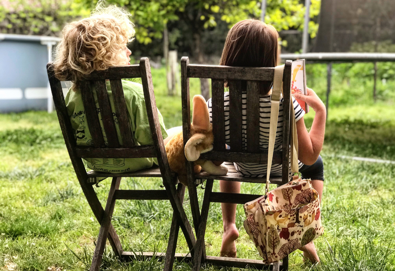 Lazy summer afternoon - two children sitting outside on chairs on the grass in the sunshine