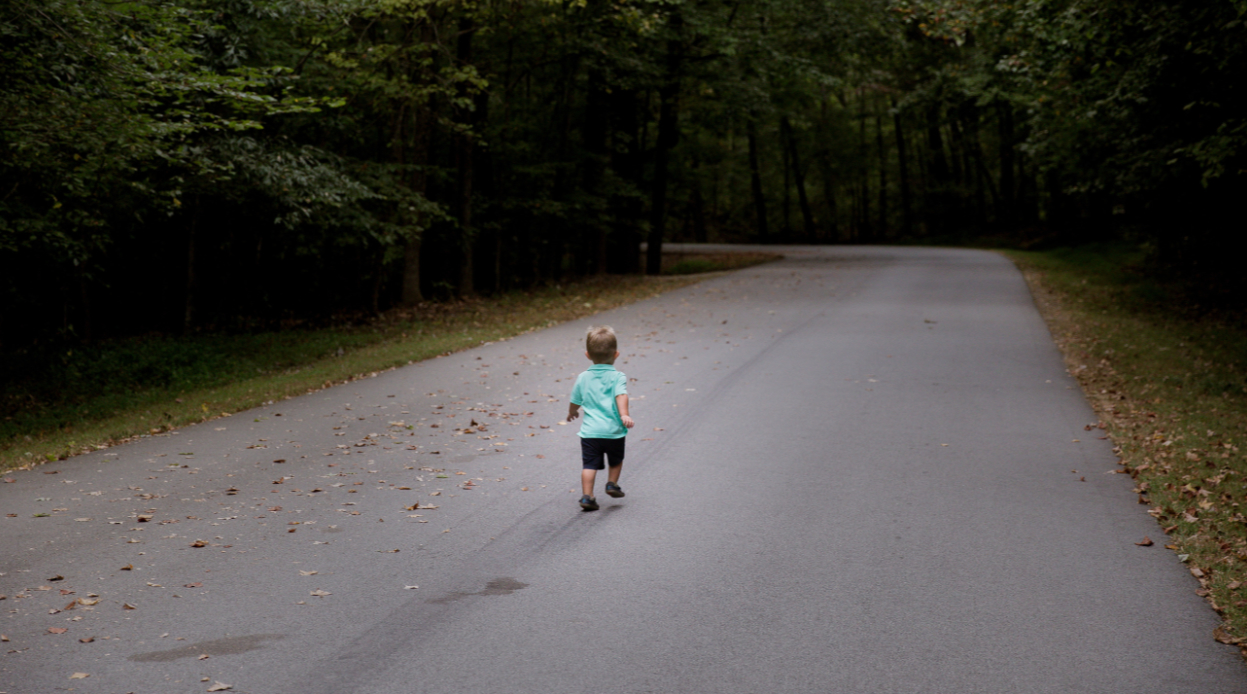 a young child walking in the middle of the road